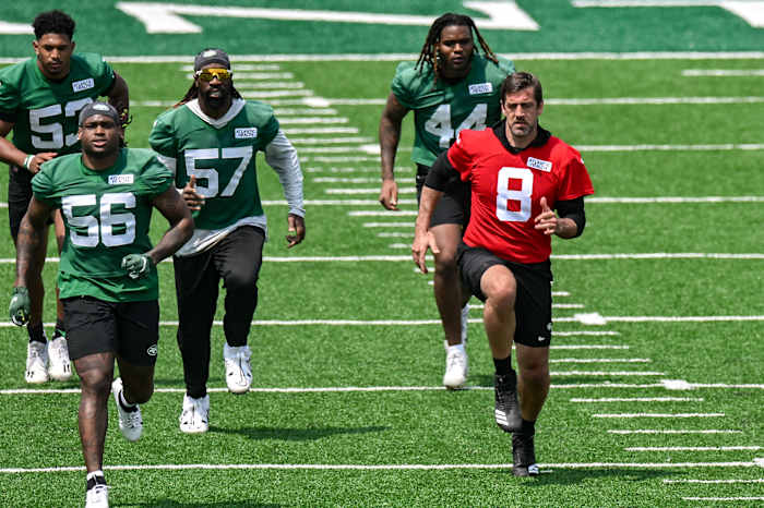 Jets players, including QB Aaron Rodgers (8), warm up at OTAs